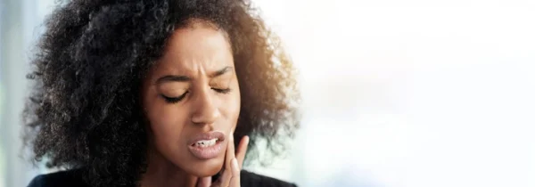 Woman holding her jaw in pain.